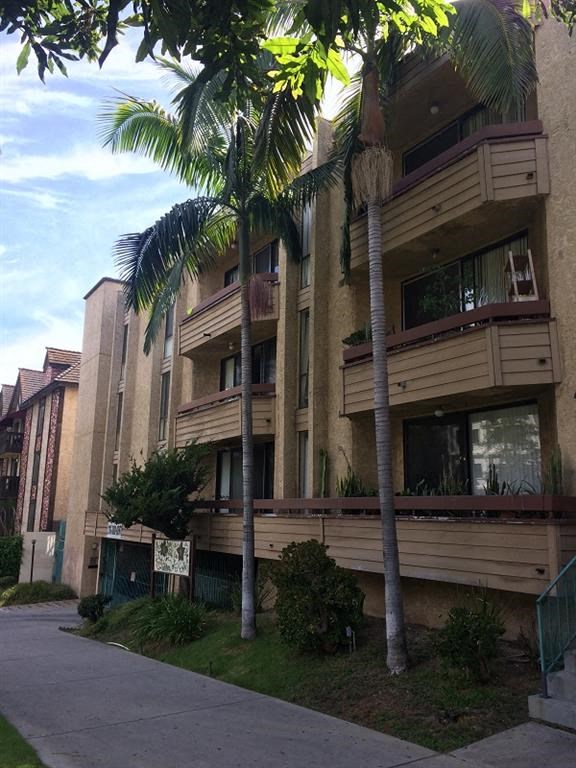 a tall apartment building with palm trees in front of it