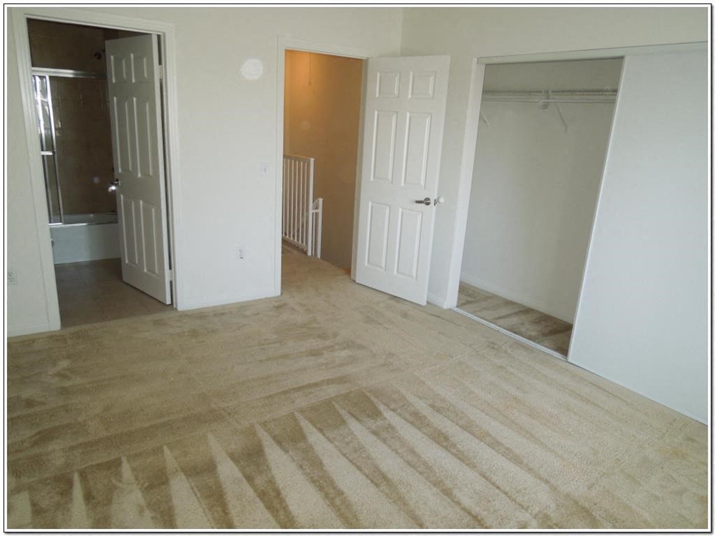 the living room and bedroom of an empty house with the door open