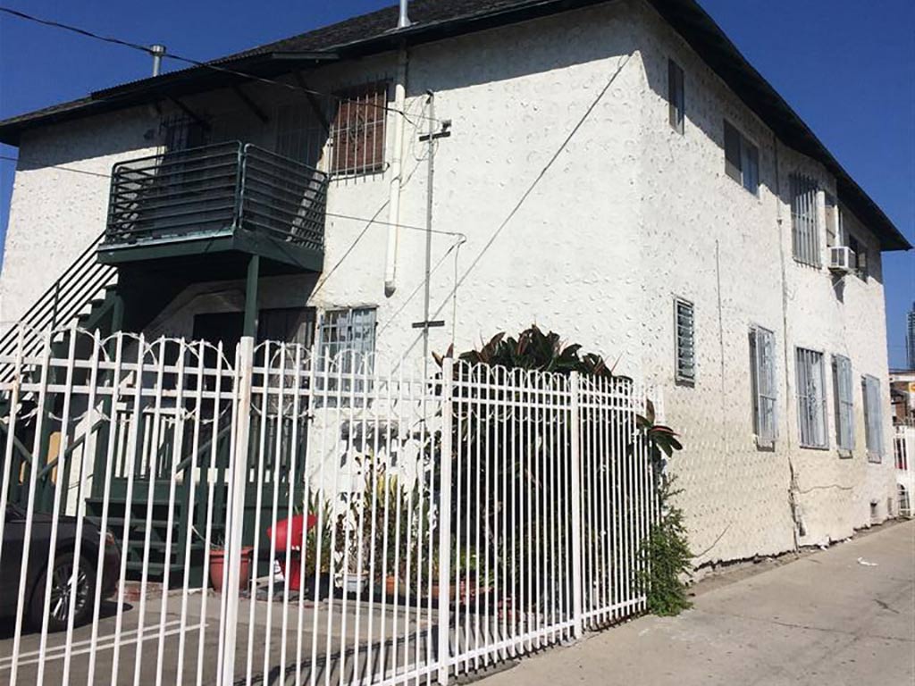 A white building with a green railing and a white fence.