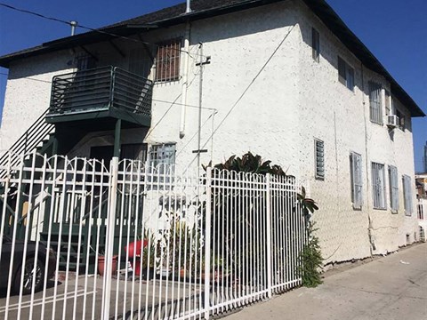 A white building with a green railing and a white fence.
