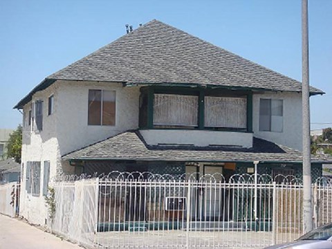A white house with a black roof and a white fence.