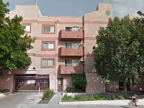 an apartment building with pink walls and trees
