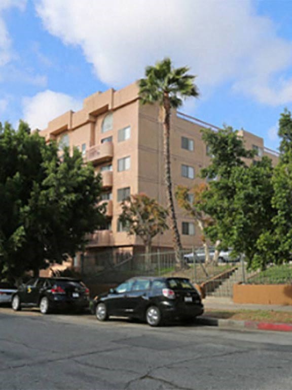 a building with a palm tree and cars parked in front of it