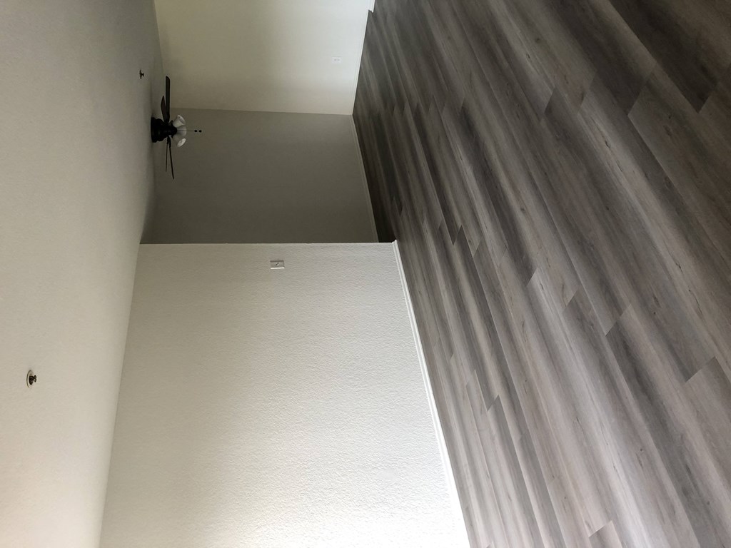 a hallway with wood flooring and white walls and a door