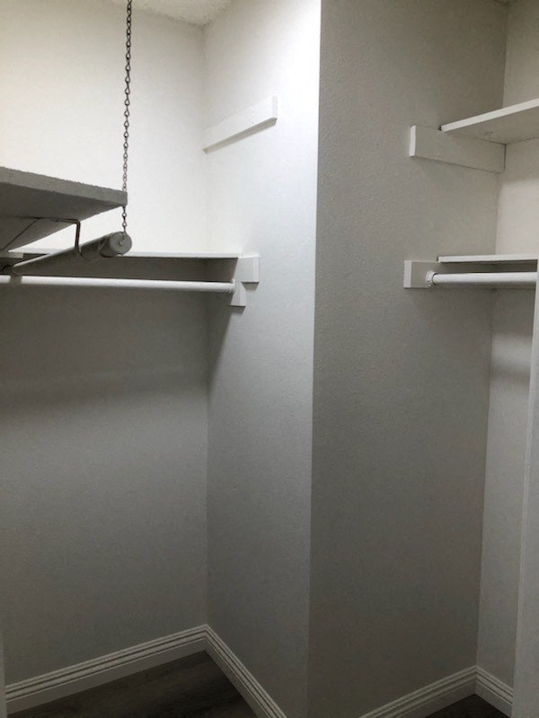 a walk in closet with empty shelves and a hanging closet organizer