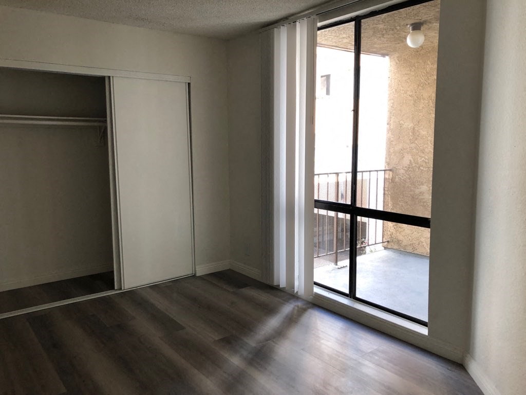 an empty living room with a sliding glass door to a balcony