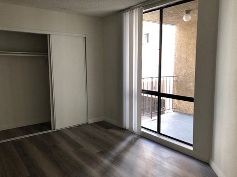 an empty living room with a sliding glass door to a balcony