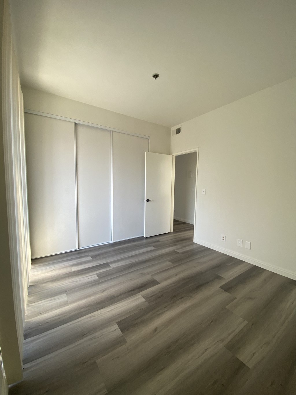 an empty living room with white walls and wood floors