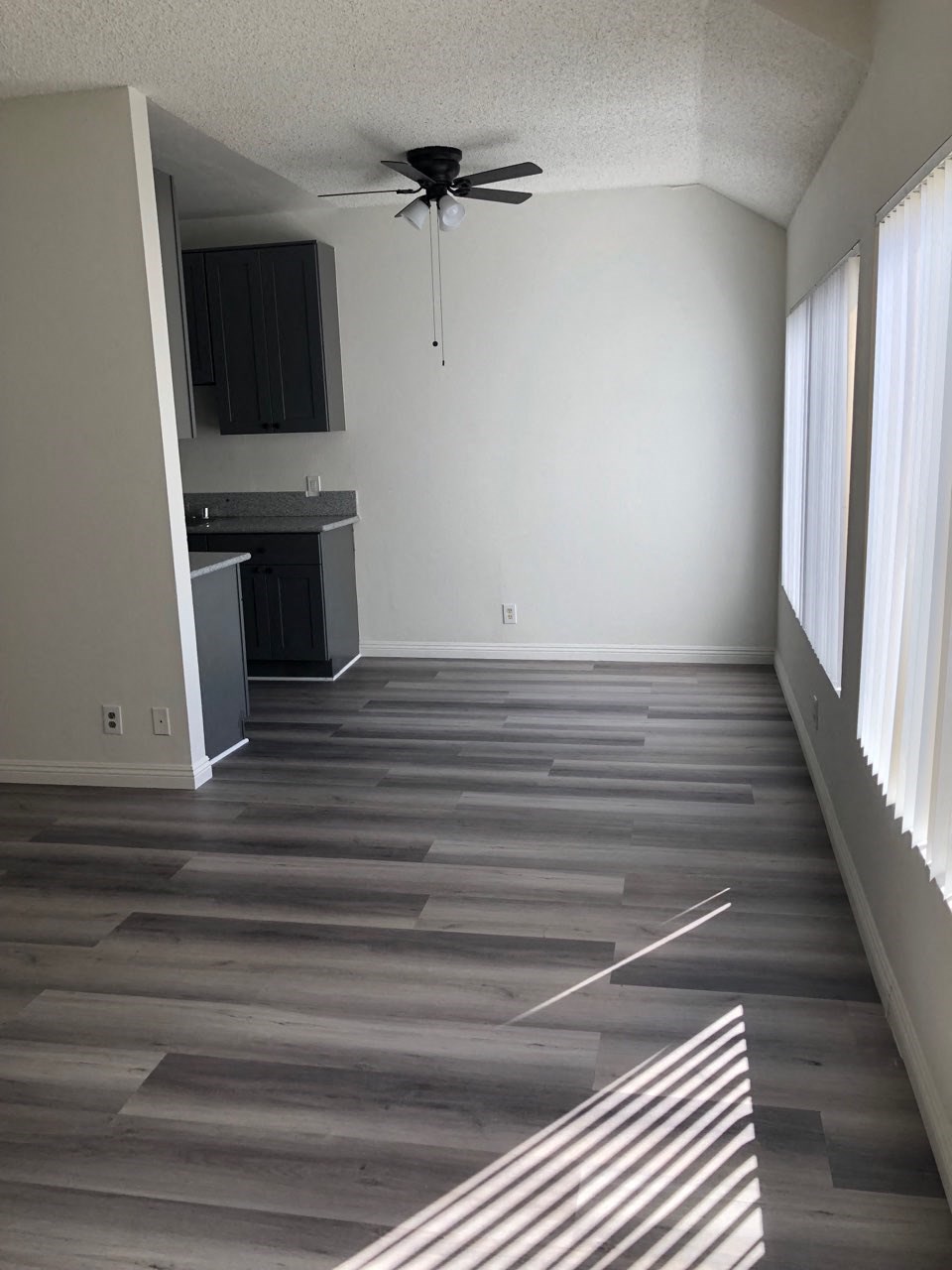 a empty living room with wooden floors and a ceiling fan