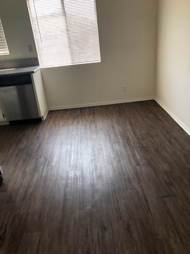 an empty living room with wooden floors and a window