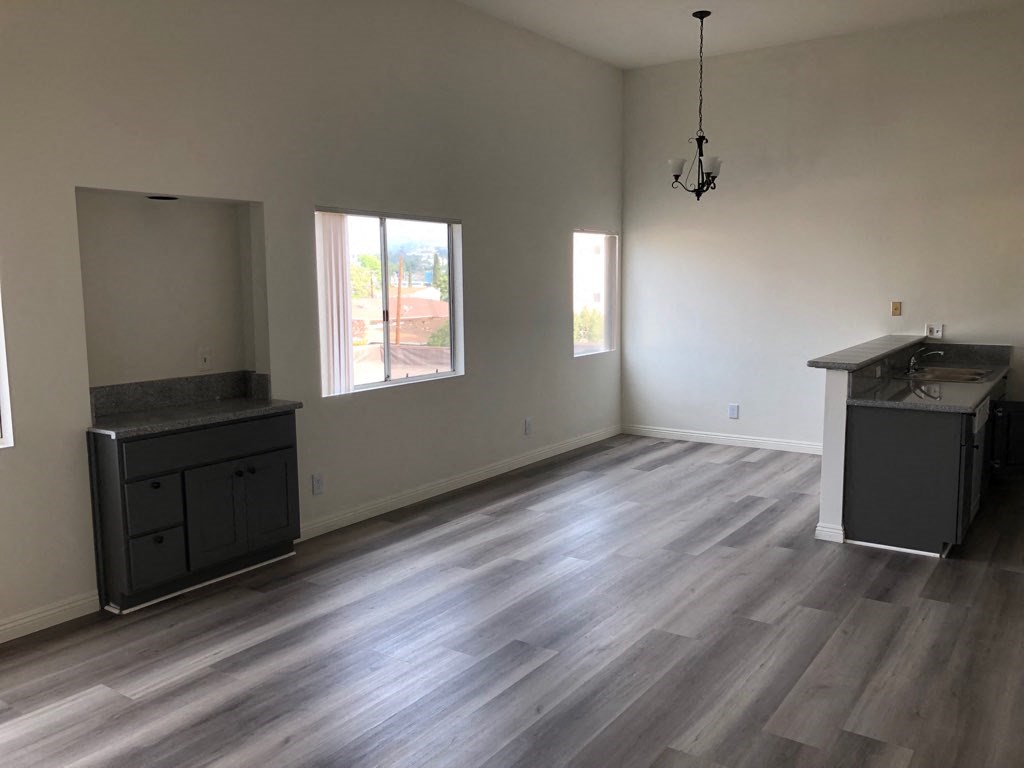 an empty living room with hardwood floors and a kitchen