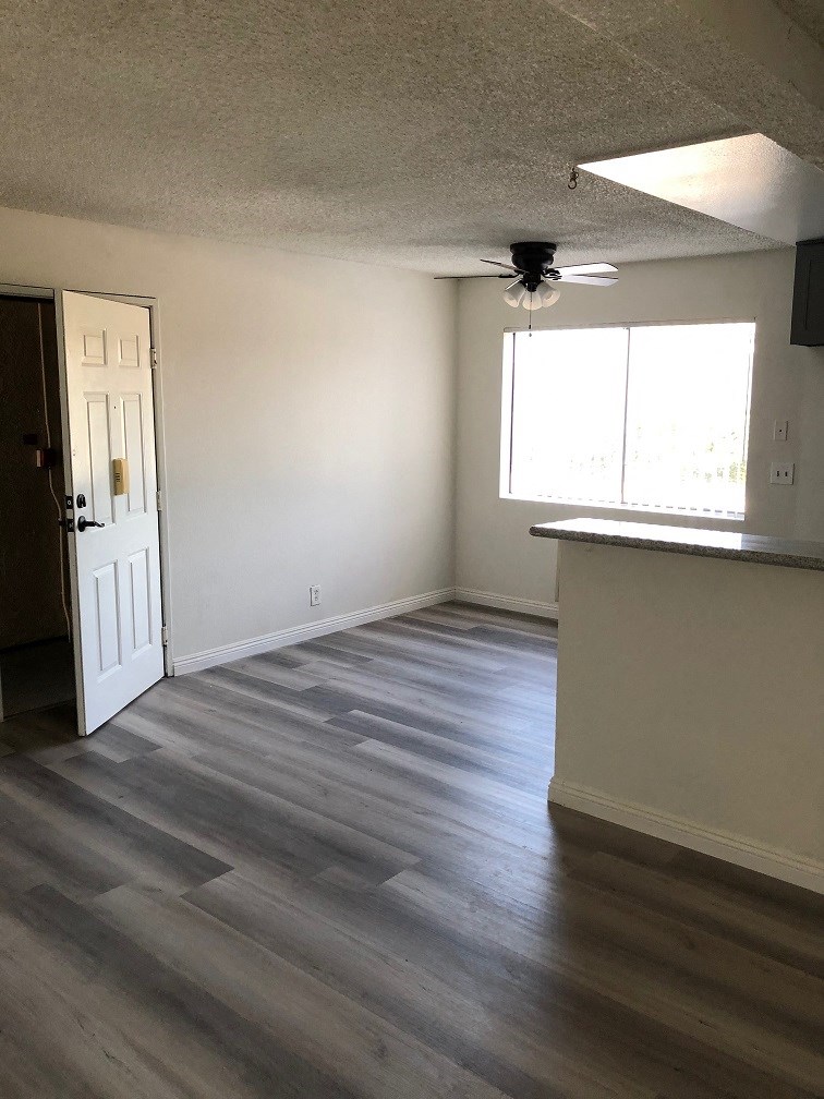 an empty living room with wood floors and a kitchen