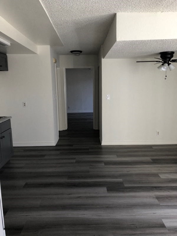 an empty living room with wood floors and a ceiling fan