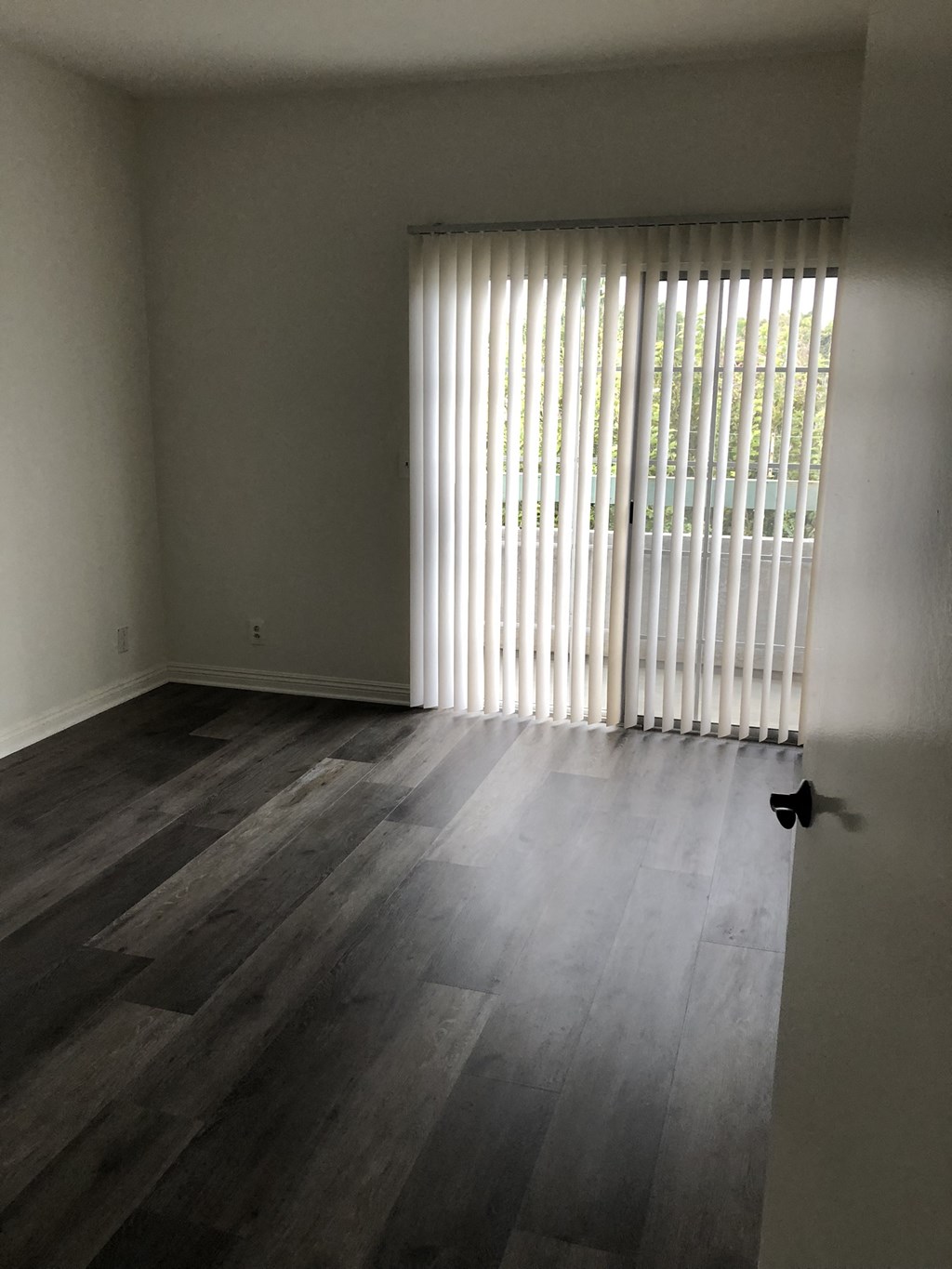 an empty living room with wood floors and a window