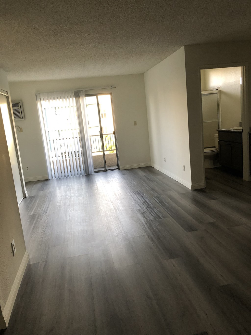 an empty living room with wooden floors and a door to a balcony
