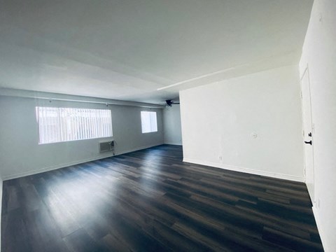 an empty living room with wood floors and white walls