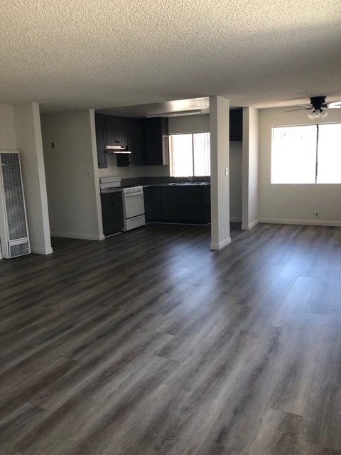 an empty living room and kitchen with wooden floors