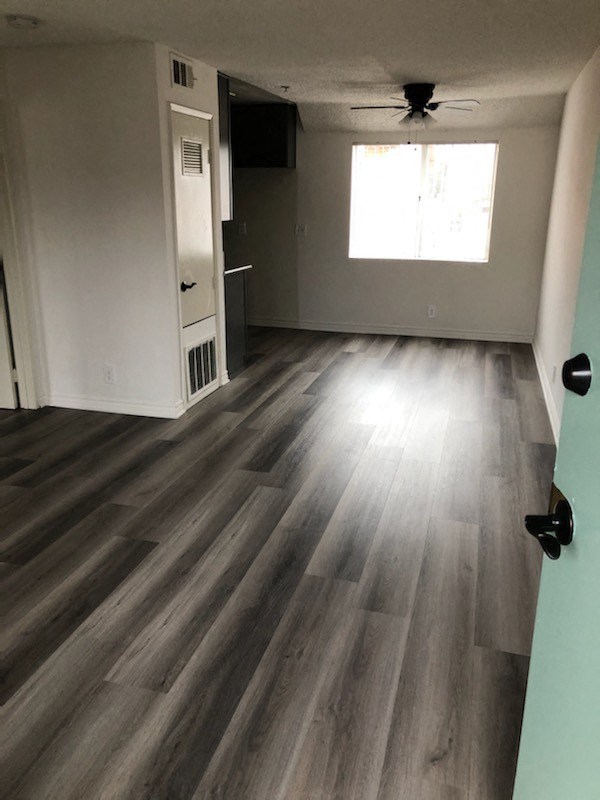 an empty living room with hardwood floors and a ceiling fan