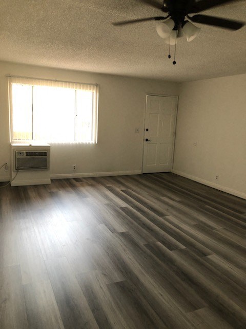 an empty living room with wooden floors and a ceiling fan