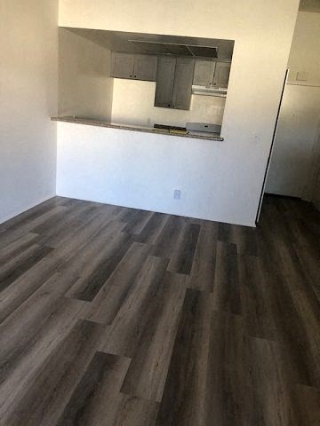 a empty room with a kitchen and wooden floors