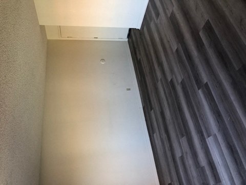 a hallway with a white wall and a wood floor