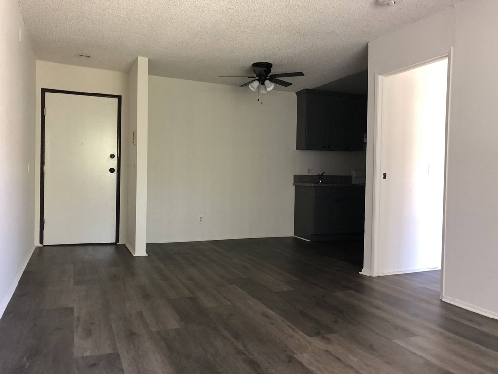 an empty living room with wooden floors and a ceiling fan