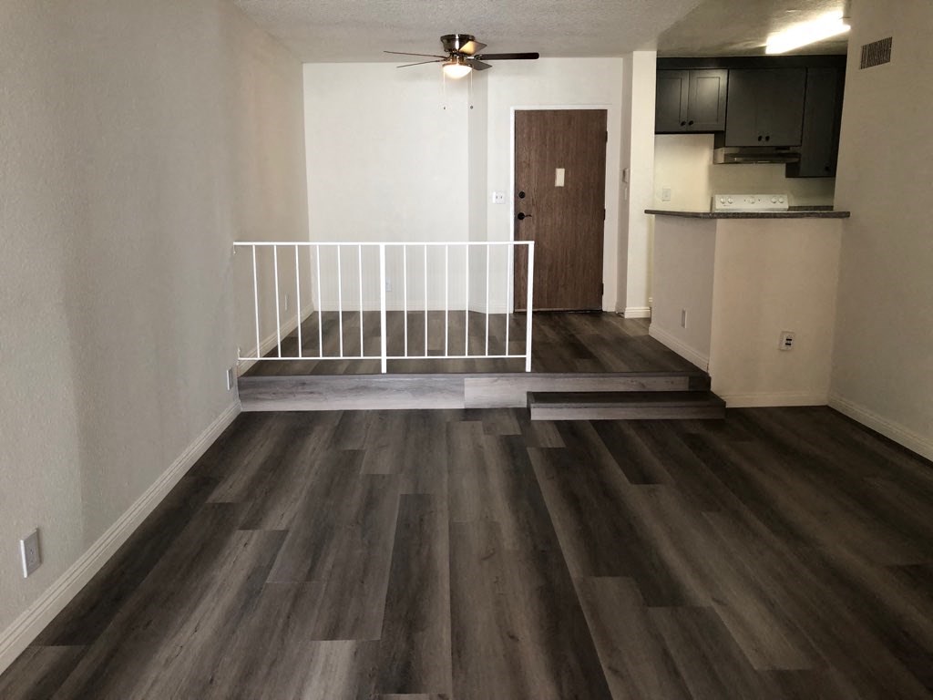 an empty living room with a white railing in the middle of it