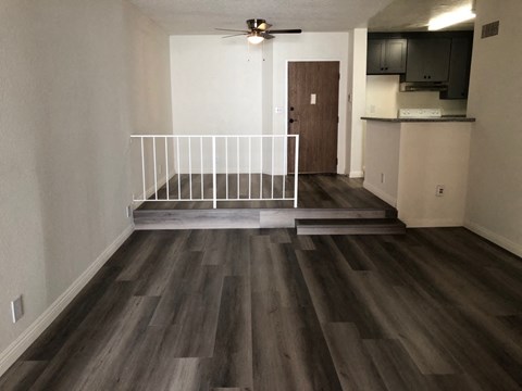 an empty living room with a white railing in the middle of it