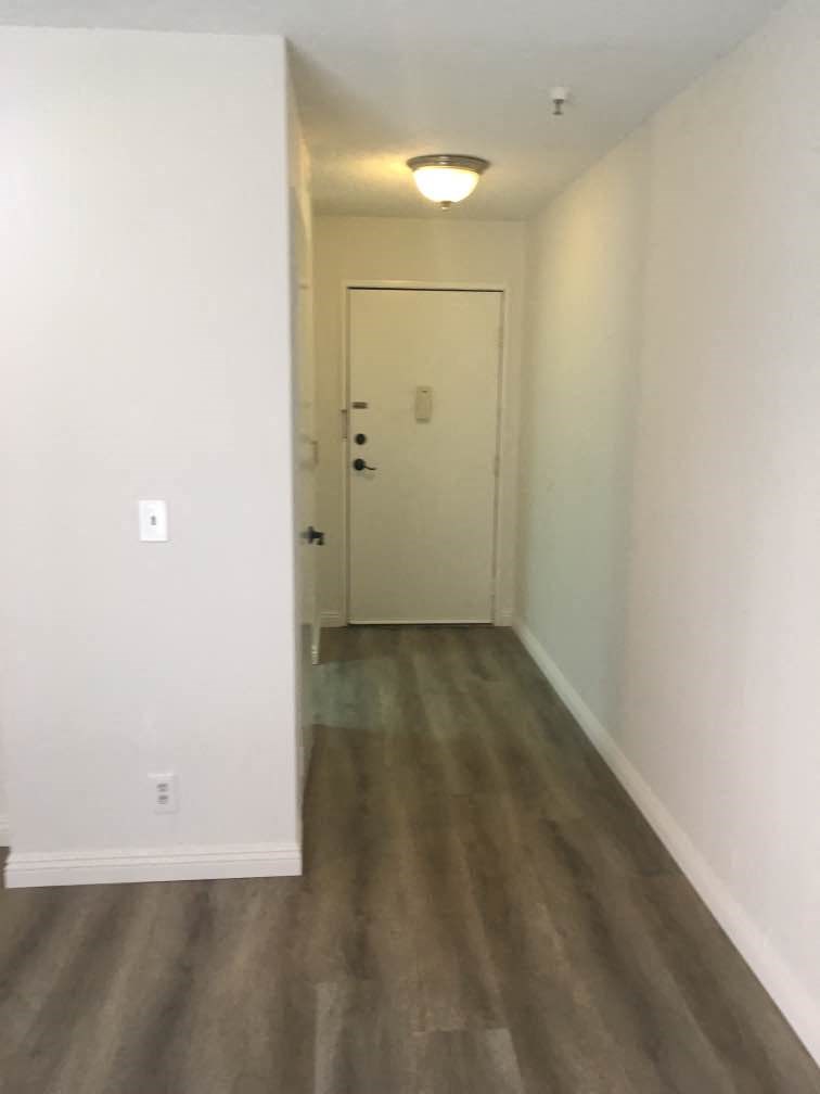 a hallway with white walls and wooden floors and a white door