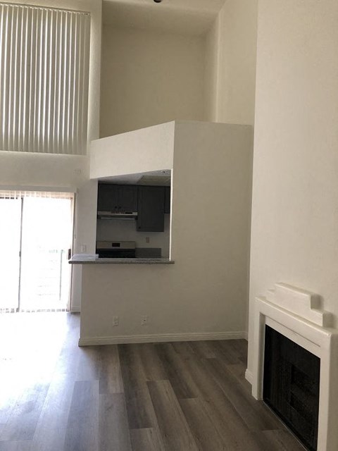 an empty living room with a fireplace and a kitchen