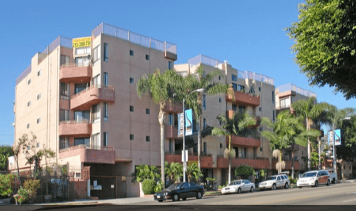 a large apartment building with cars parked on the street