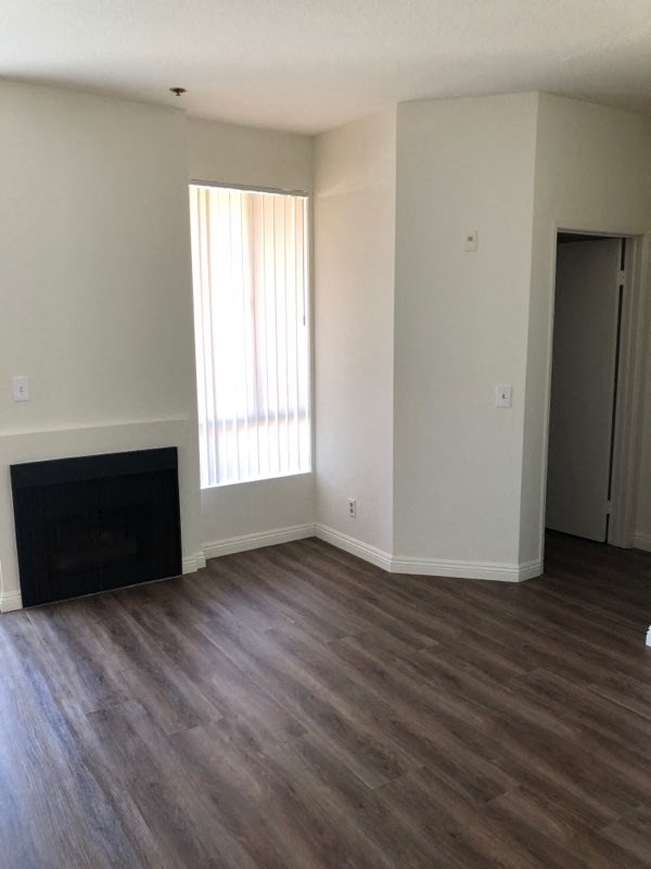 an empty living room with wooden floors and a fireplace