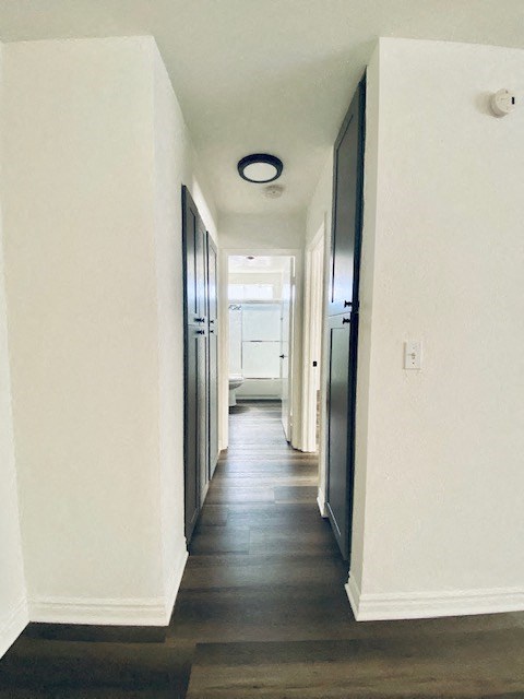 a hallway with wood floors and white walls and a black door