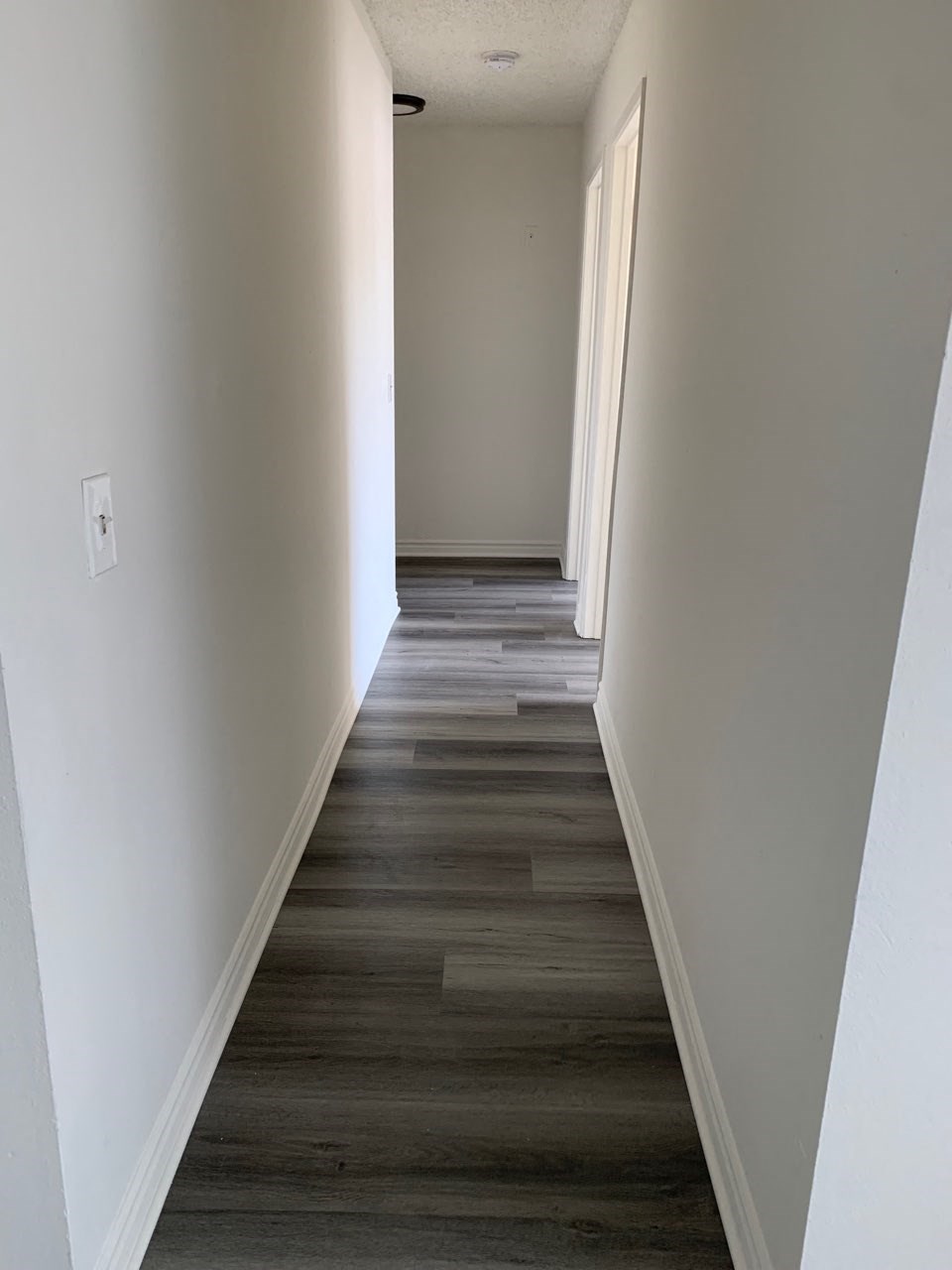 a view down a hallway with wood floors and white walls