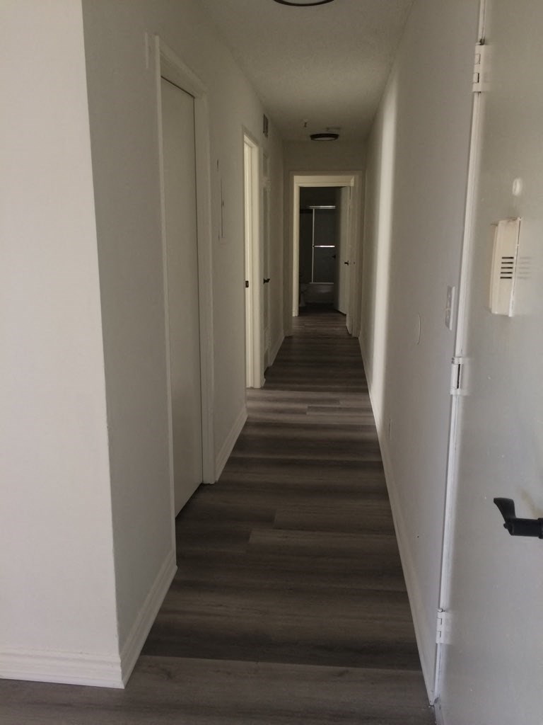 a long hallway with wood floors and white walls and a door