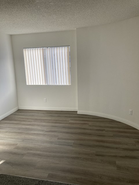 an empty room with wooden floors and a window