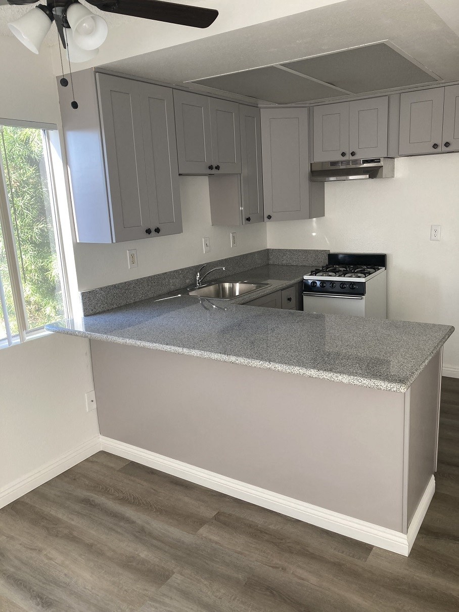 an empty kitchen with gray countertops and white cabinets