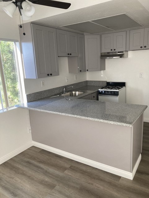 an empty kitchen with gray countertops and white cabinets