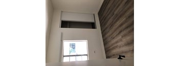 A window with a view of a building outside is in a room with a wooden wall.
