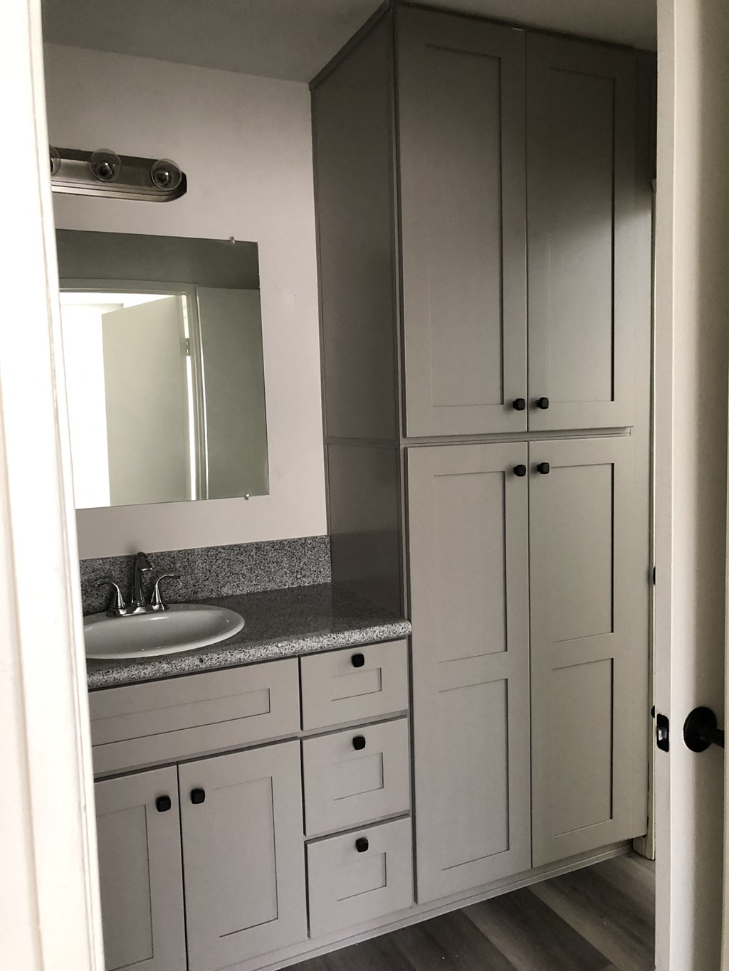 a bathroom with white cabinets and a sink and a mirror