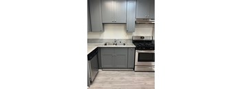 A kitchen with a stove, sink, and cabinets.