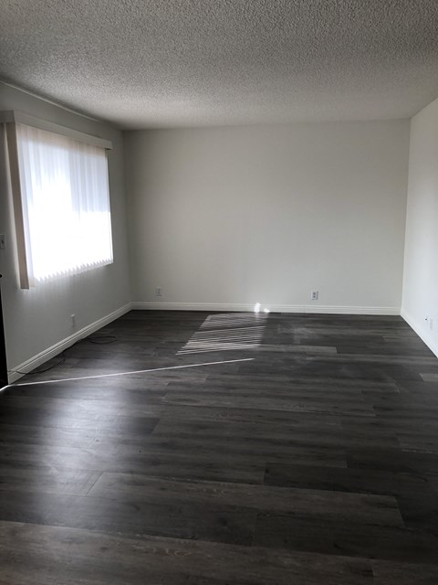 an empty living room with wood floors and a window