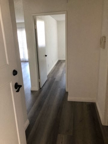 a hallway with wood floors and white walls and a door