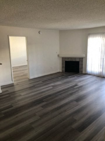 an empty living room with wooden floors and a fireplace