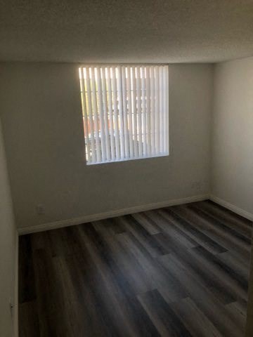 an empty room with a window and wooden floors