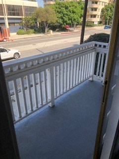 a balcony with a view of a street and a white railing