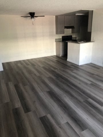 a living room with wooden floors and a kitchen