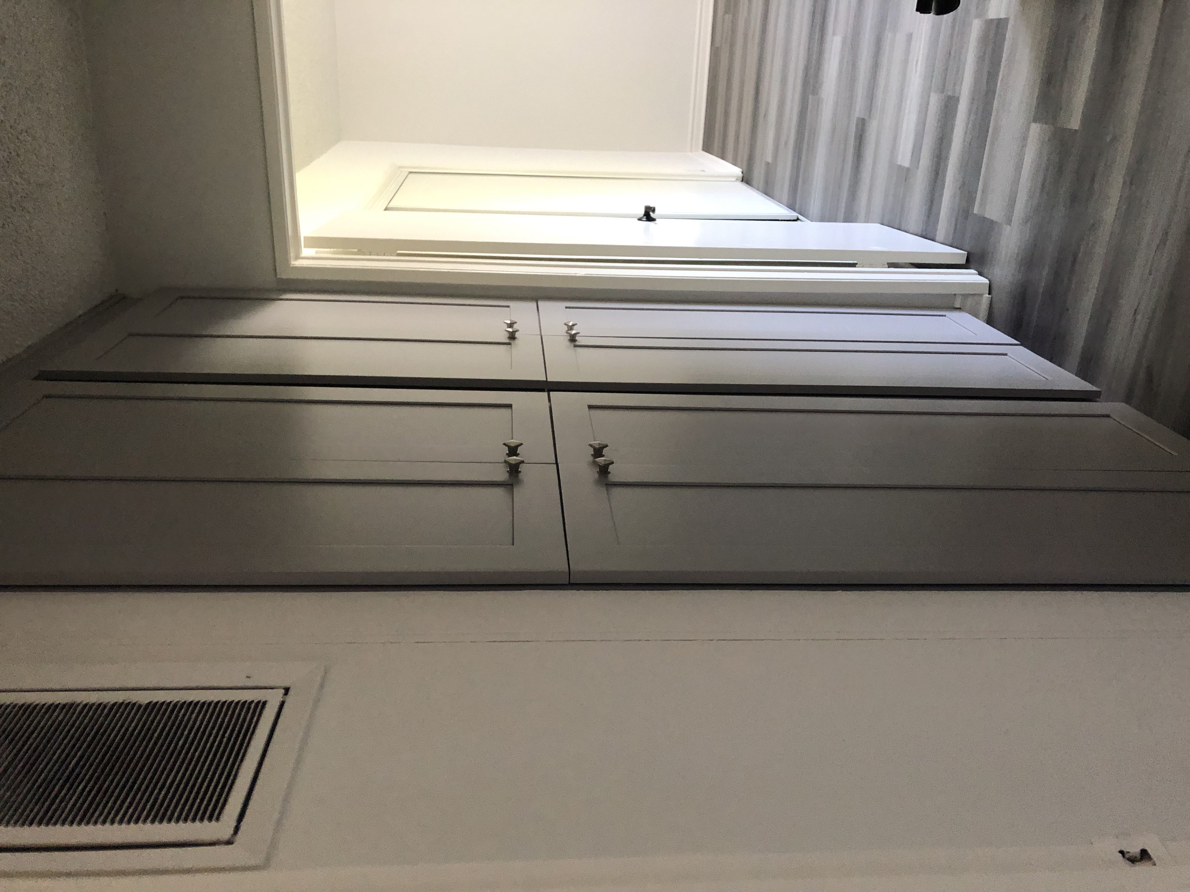 A white cabinet with a vent underneath it.