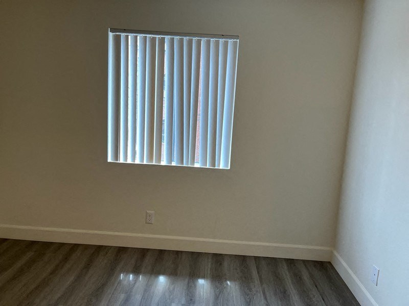 an empty room with a window with vertical blinds