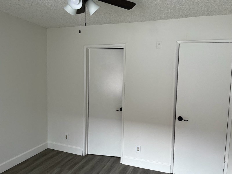a bedroom with white walls and a closet and a ceiling fan